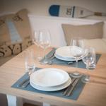 Dining table set for two with kitchen seating in the background.