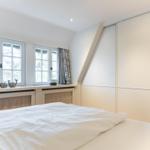 Schlafzimmer mit Dachschrägen, Fenstern und Schlafplatz.
