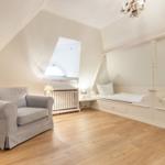 Schlafzimmer mit zwei Einzelbetten und Sessel unter schrägen Dachschrägen.