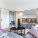 Wohnzimmer mit Sofa, TV und Schwebetüren. Wandbild zeigt Strand.