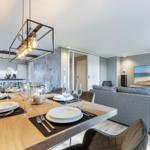 Essbereich mit Tisch und Stühlen, Küche und Wohnzimmer mit Sofa und Fernseher