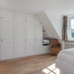 Bedroom with white closet, bed, chair, and window.