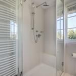 Shower cabin with showerhead, window, and heater.
