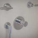 Showerhead with rotary control and two levers on white wall