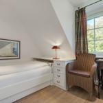 Bedroom with bed, desk, and chair. Window with curtain. Wall picture and nightstand.