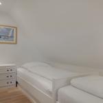 Room with two beds, dresser, and wall art on sloped ceiling.