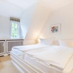 Bedroom with double bed, two windows, and a chair.