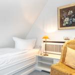 A bedroom with bed, chair, and wall painting.