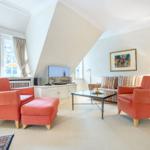 Living room with two orange chairs, sofa, and TV.