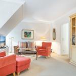 Living room with red armchairs, sofa, and glass cabinet.