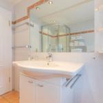 Badezimmer mit Waschbecken, Spiegel und Dusche.