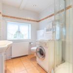 Badezimmer mit Dusche, Waschmaschine und Fenster.