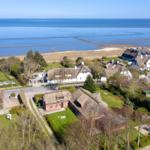 Dorf mit Strohdächern am Meer mit Blick auf Watt und Schilf