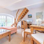 Wohn- und Essbereich mit Holztreppe und Glastür zum Garten
