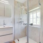 Dusche mit Glaswand, Waschbecken und Spiegelschrank