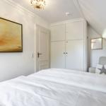 Schlafzimmer mit weißem Bett, Kleiderschrank und Wandbild.