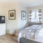 Bedroom with bed, TV, and window with curtains.