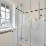 Shower cabin with glass enclosure and window overlooking outside.