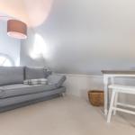 A room with gray sofa, desk and standing lamp under a vaulted ceiling.
