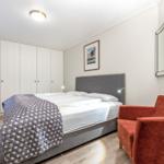Bedroom with bed, wardrobe, armchair, and mirror.