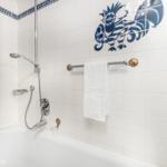 Bathroom with bathtub, showerhead, and blue-white tiles