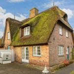 House with thatched roof and brick facade.