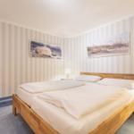 A bedroom with wooden bed, striped walls, and two wall pictures.