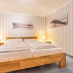 Bedroom with wooden bed, striped walls, and nightstands with lamps.