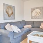 Grauer Sofa mit Kissen und Wandbildern von Muscheln.