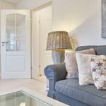Ein Wohnzimmer mit grauem Sofa, Kissen und einer Lampe.