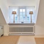 Dachgeschosszimmer mit Fenster, zwei Lampen und Modellboot.