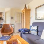 Living room with sofa, chair, and kitchen area in the background.