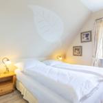 Double bed with white linens, nightstand, and wall decoration