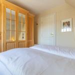 Bedroom with double bed, wooden wardrobe, and two pictures on the wall.