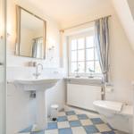 Bathroom with shower, sink and toilet under sloped ceiling.