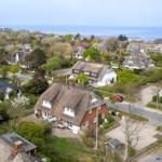 Village with thatched houses and view of the sea.