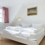 Schlafzimmer mit weißem Bett, Fenster und Bild an der Wand.