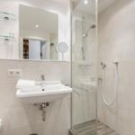 Bad mit Dusche, Waschbecken und Spiegel