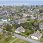 Aerial view of a coastal village with traditional houses and greenery.