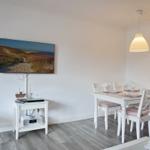 Essbereich mit weißem Tisch und Stühlen, Fernseher und Wandbild