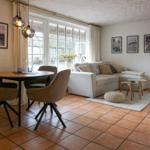 Wohn- und Essbereich mit Sofa, Tisch und Stühlen. Terrasse mit Blick durch Fenster.