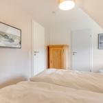 Schlafzimmer mit Bett, Kleiderschrank und Wandbildern