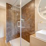 Moderne Dusche mit Glaswand und Waschbecken mit runder Spiegel