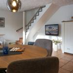 Esszimmer mit runder Tisch, Stühlen und Treppenaufgang.