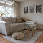 Wohnzimmer mit Eckcouch, Glas-Tischen und Fenster mit Blick nach draußen.