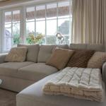 Ein Sofa mit Kissen und Decke vor einem Fenster mit Blick auf die Natur.