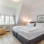 Schlafzimmer mit Doppelbett, Fenster und Sessel.