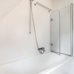 Bad mit Badewanne, Duschwand und Handbrause.