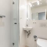 Dusche mit Duschbrause, Waschbecken und WC in weißer Ausführung.