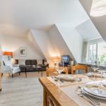Essbereich mit Tisch und Stühlen. Wohnbereich mit Sofa und Kamin. Holzmöbel und Fenster.